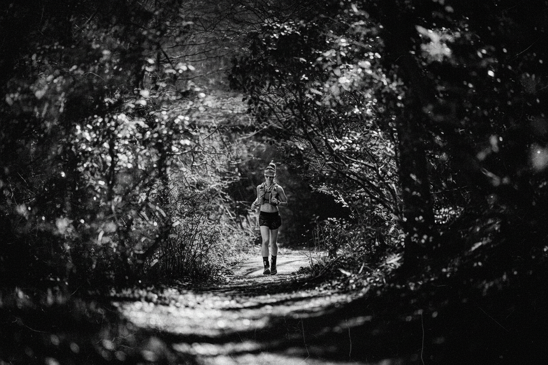 Trail runner moving through a wooded path during an endurance race